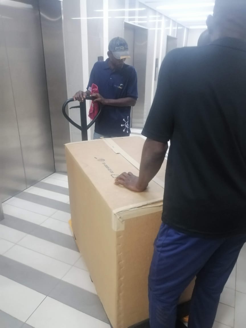 PackPro team member in branded uniform moving a large crate with a pallet jack